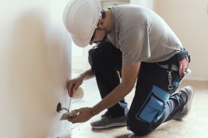 Professional electrician installing sockets using a screwdriver: home renovation and maintenance concept