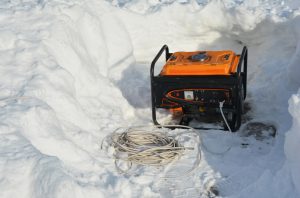 A portable generator, backup power generator around snow after severe winter weather, blizzard and snow storm. Using a mobile generator to provide power after snowy weather.